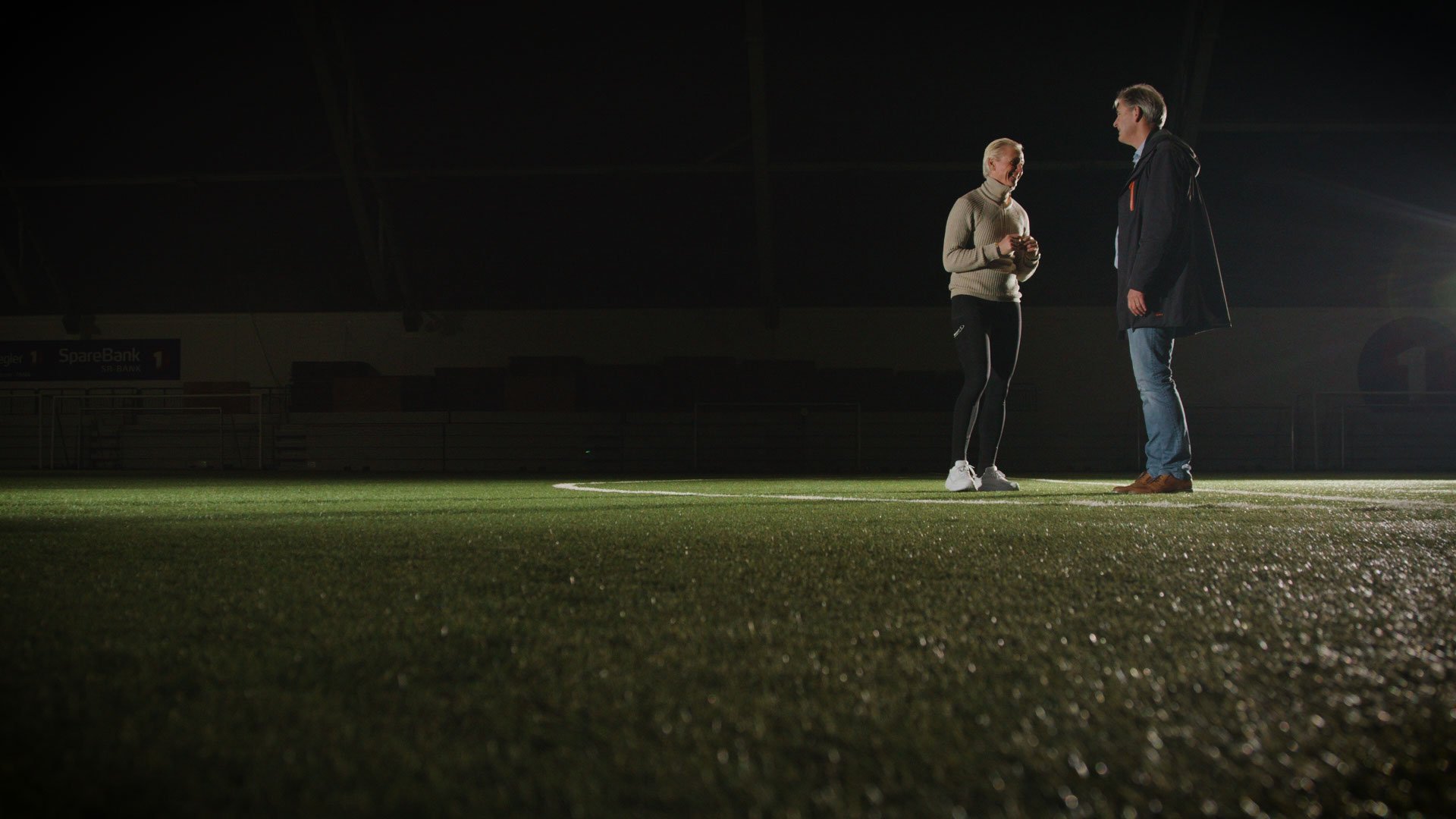 2 personer på en fotballbane, i mørket